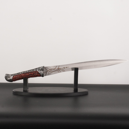 Decorative knife with a detailed handle on a stand against a plain background