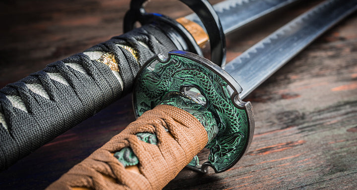 Close-up of two traditional Japanese katana swords with wrapped handles and decorative dragon tsuba resting on a wooden surface.
