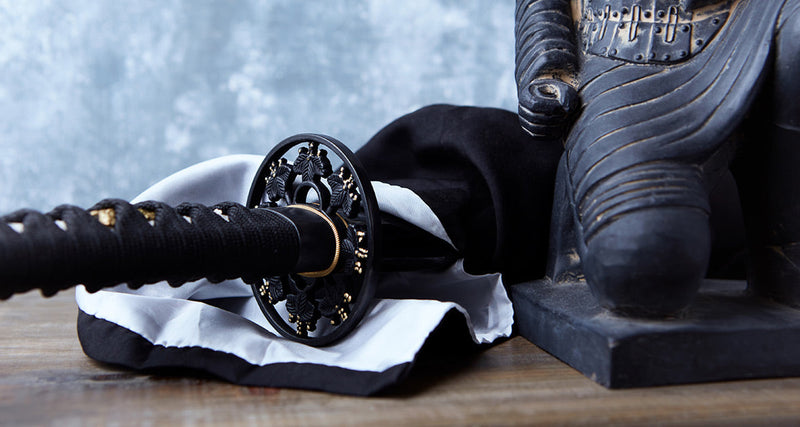 Close-up of a decorative katana resting beside an elephant statue.