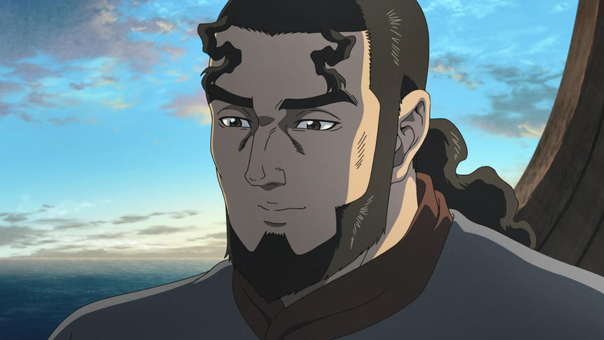 Animated close up of a bearded man with a ponytail and distinctive curled bangs, standing near the ocean under a cloudy sky