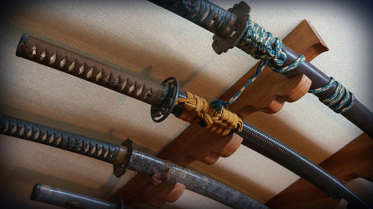 "Close-up of traditional Japanese katana handles and scabbards displayed on a wooden sword rack, featuring detailed tsuka-ito and sageo cords."