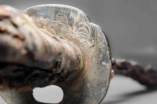 Close-up of a rusted samurai sword guard and handle with worn engravings.