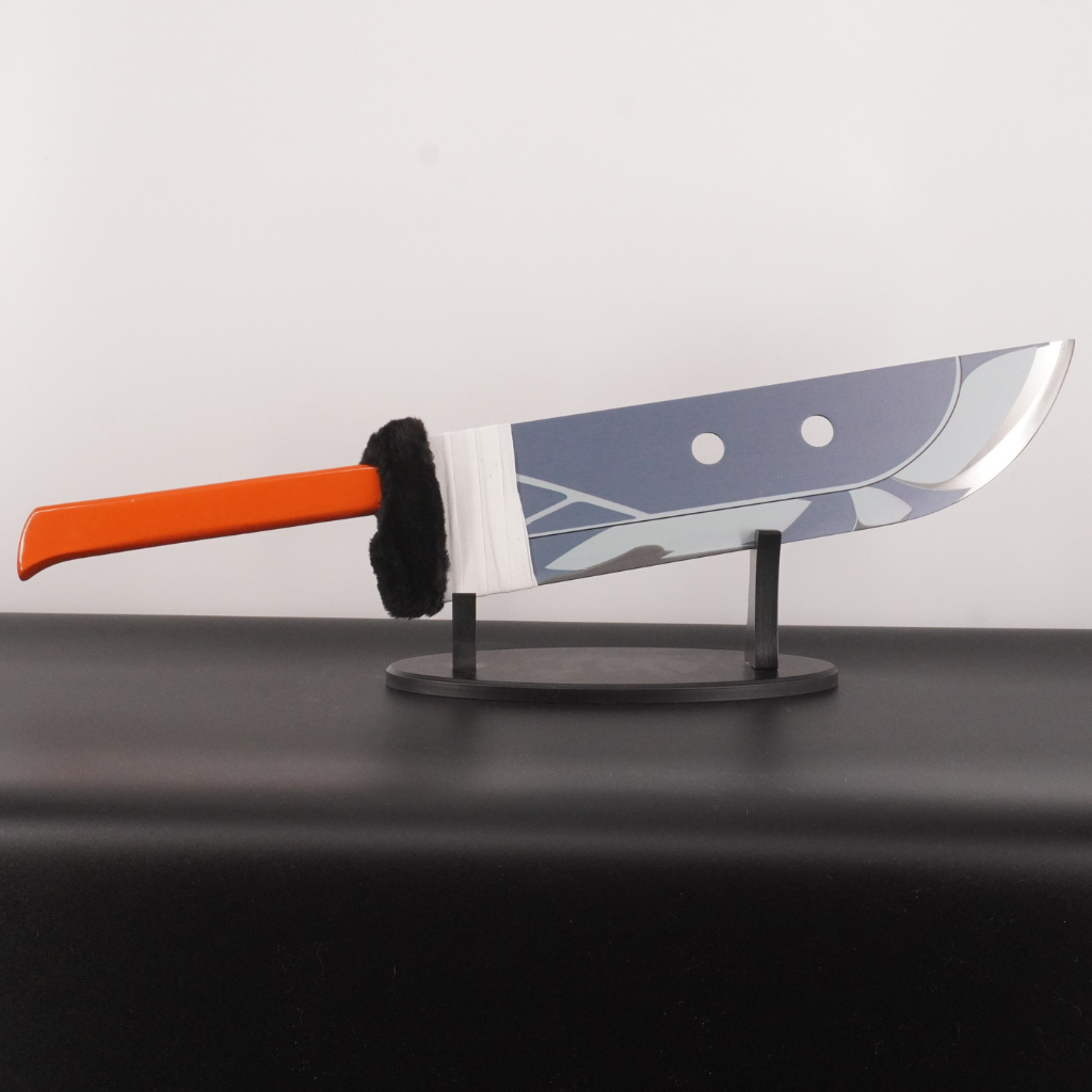 Knife with orange handle and camouflage blade on a stand against a white background