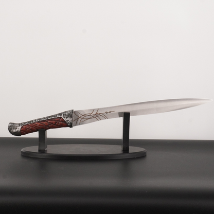 Decorative knife with a detailed handle on a stand against a plain background